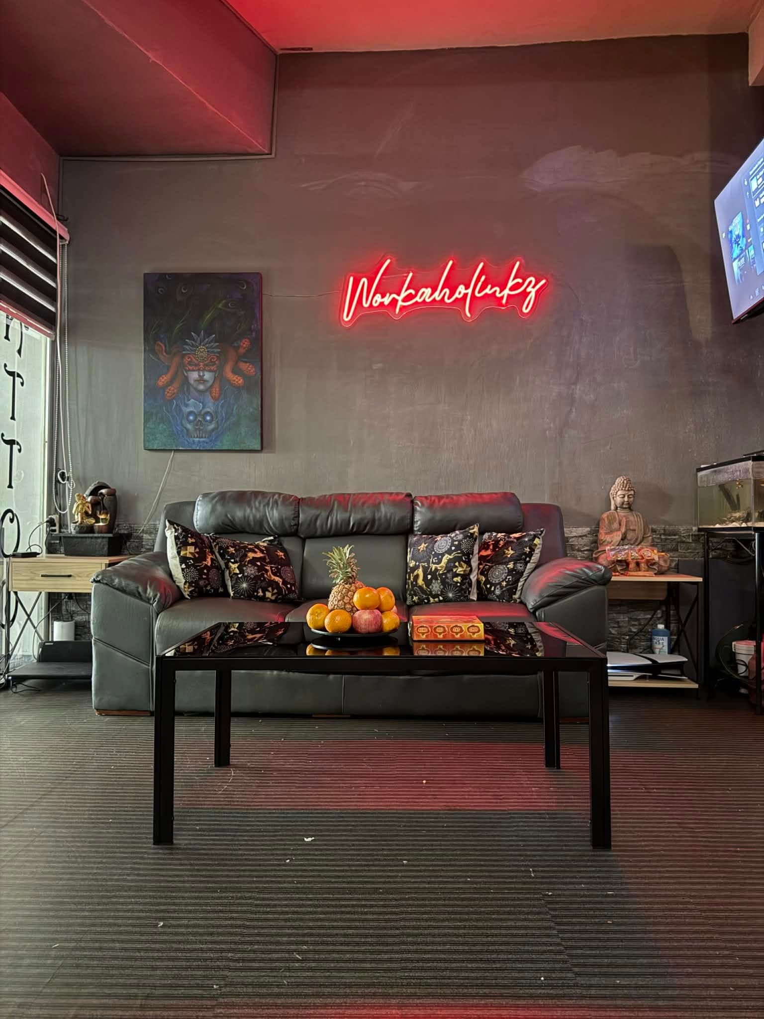 Studio lounge with a leather sofa below the red neon Workaholinkz sign