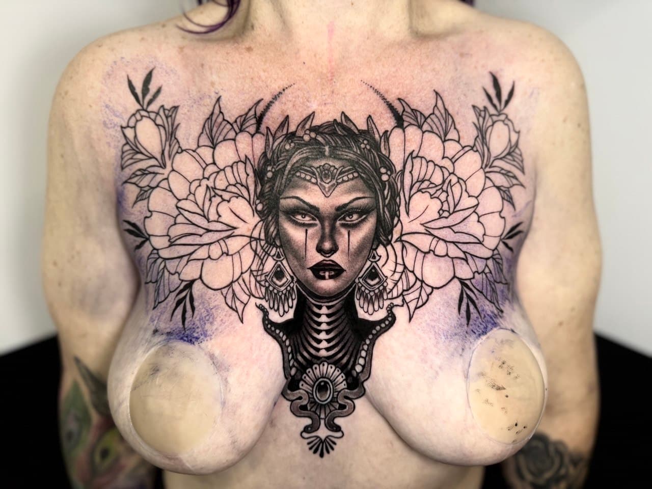 Black and grey portrait and floral chest tattoo