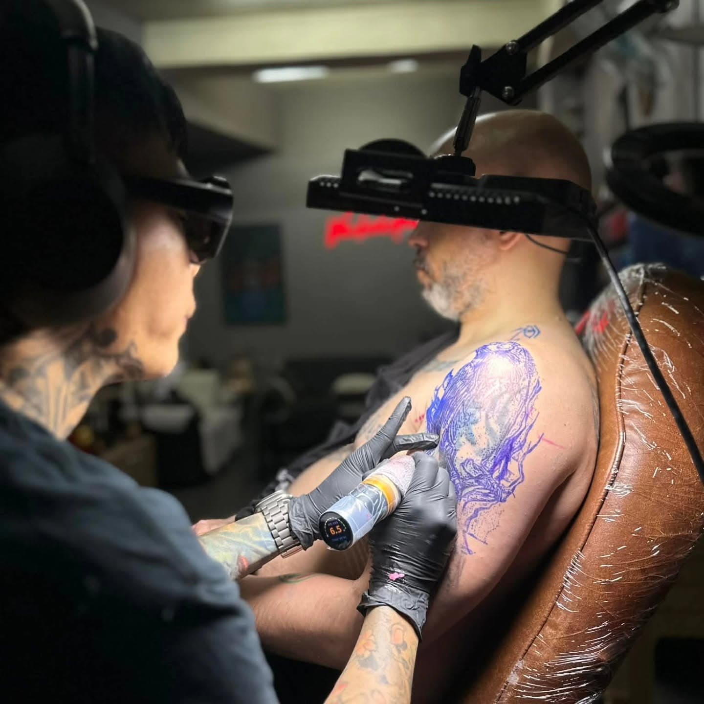 Tattoo artist working on a stenciled upper-arm design