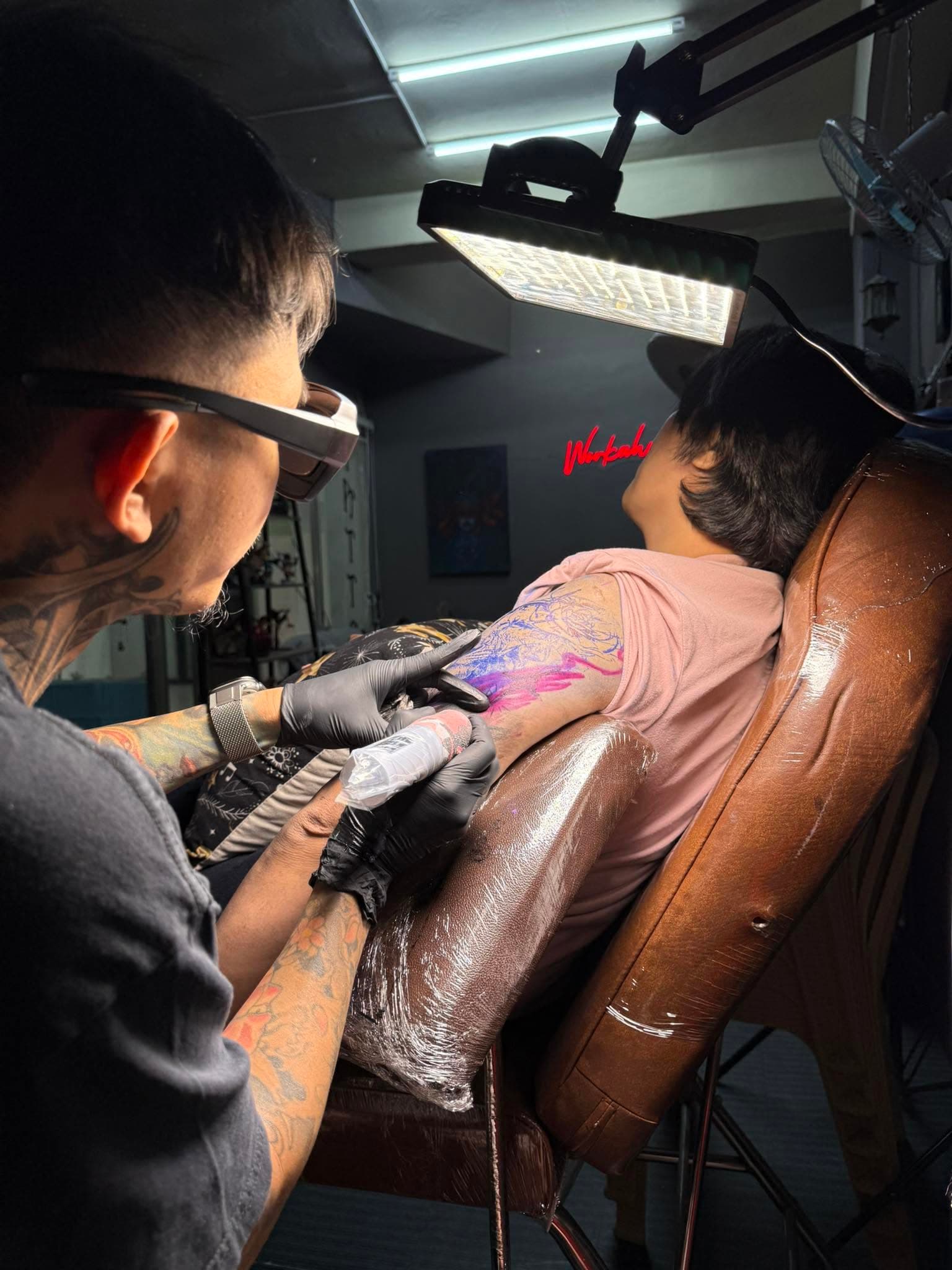 Close-up of a tattoo artist concentrating on an arm tattoo