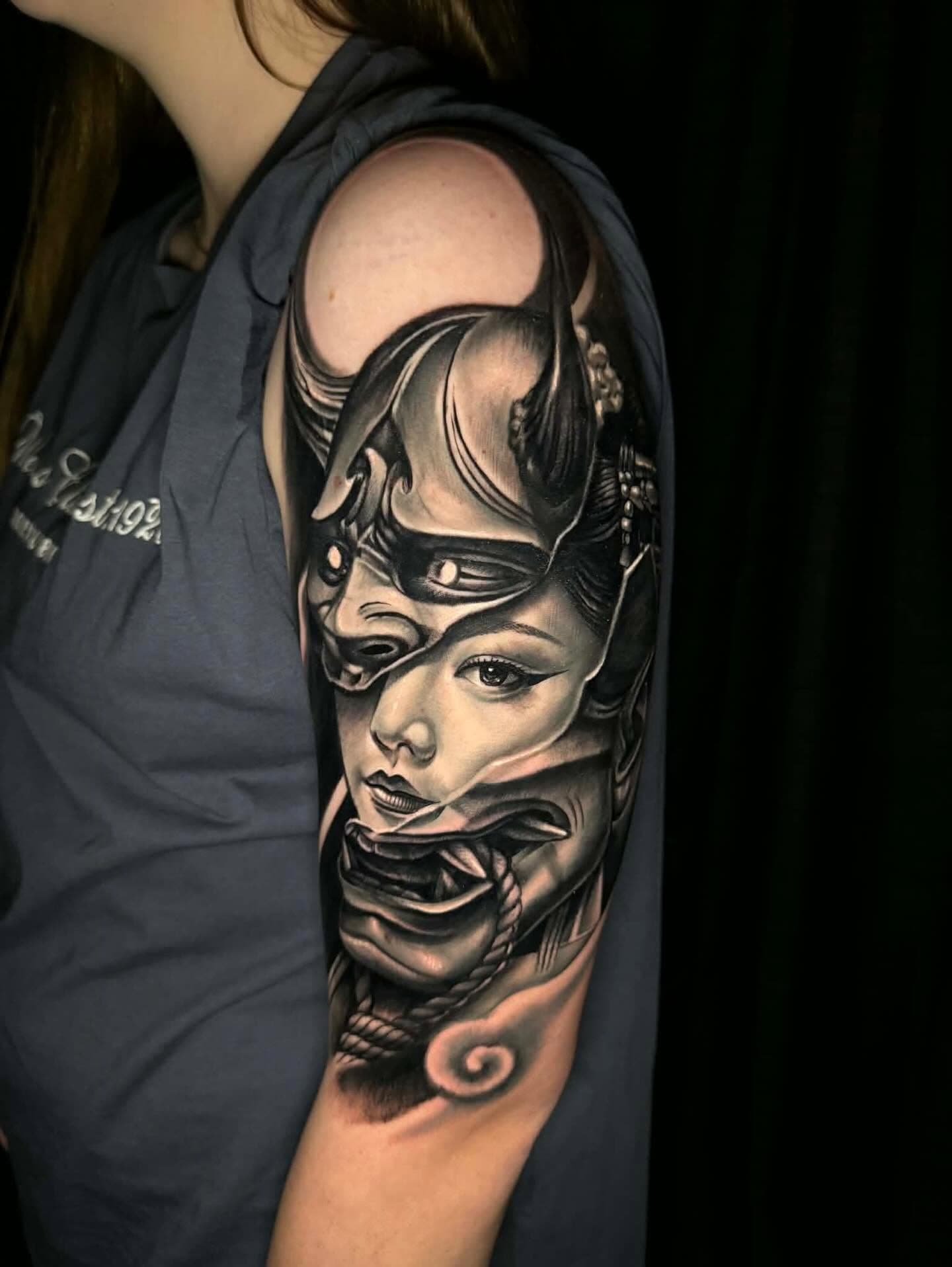 Black and grey woman in a samurai helmet tattoo on an upper arm