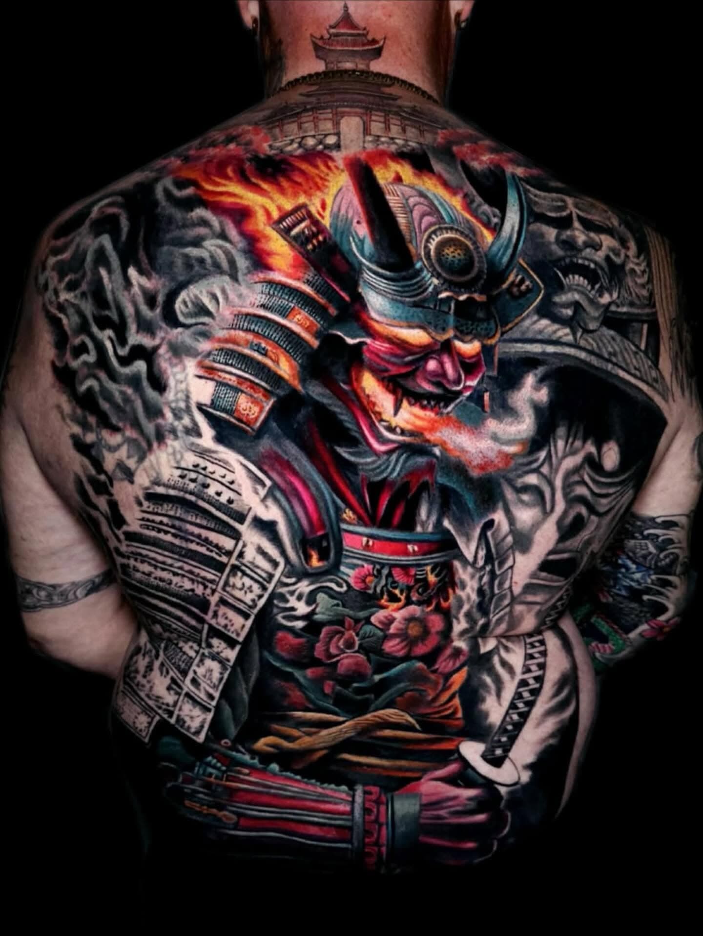 Full-back samurai tattoo with red armor, flames, and detailed black shading