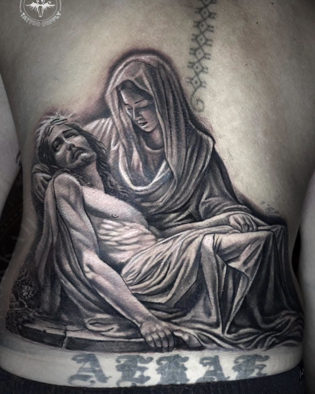 Black and grey religious scene of Mary holding Jesus tattooed on a torso